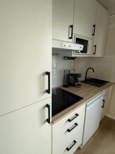 eine kleine Küche mit weißen Schränken und einer Mikrowelle in der Unterkunft La Naturelle 123 - Duplex Vue Mer Wimereux in Wimereux