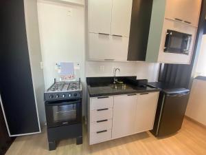 a small kitchen with a stove and a sink at Apt completo: ar cond piscina e academia no Centro in Taubaté
