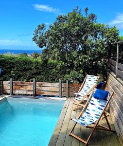 two deckchairs and two lawn chairs next to a swimming pool at Casa Baia Hendaye in Hendaye