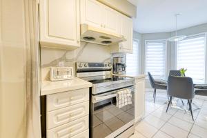 a kitchen with white cabinets and a stove top oven at The Urban Family Pad in Toronto