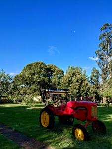 a red tractor sitting in the grass in a park at La Posada del Mar in Miramar
