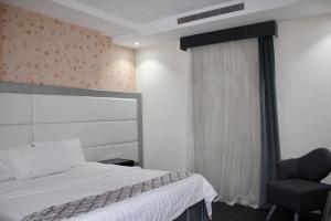 a bedroom with a bed and a chair next to a window at Shouel Inn Furnished Apartments in Makkah +10 photos
