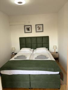 a large green bed in a bedroom with two lamps at Apartman *Joy* in Osijek