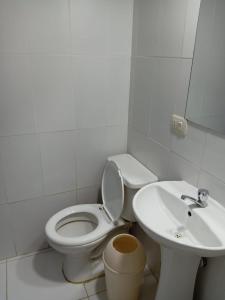 een witte badkamer met een toilet en een wastafel bij Casa Hospedaje Sunya in Cuzco