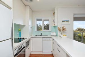 Una cocina blanca con fregadero y ventana. en Royal Surf - Beach Front Paradise, en Narrabeen 8 fotos más