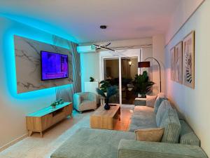 een woonkamer met een bank en een tv aan de muur bij Angelo Maison in Thessaloniki