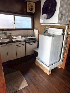 een kleine keuken met een spoelbak en een fornuis bij Hikari Kitaayase - 光莉 北綾瀬 - 浅草や上野へアクセス良好 MAX11名の和風宿 無料Wi-Fi in Tokyo