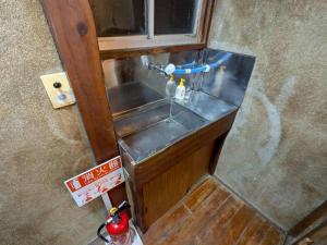 een kleine wastafel in een kleine kamer met bij Hikari Kitaayase - 光莉 北綾瀬 - 浅草や上野へアクセス良好 MAX11名の和風宿 無料Wi-Fi in Tokyo