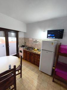Una cocina con un refrigerador blanco y una mesa. en El Dorado Deptos a una cuadra del mar, en San Bernardo