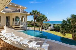 Chateau of the Isle by Emerald Isle Realty في Salter Path: منزل مع مسبح وكراسي والمحيط