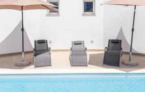 three chairs and umbrellas next to a swimming pool at Cozy Apartment In Marzamemi With Swimming Pool in Marzamemi +10 photos