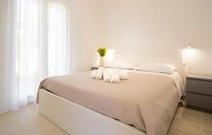 a white bedroom with a bed with towels on it at Cozy Apartment In Marzamemi With Swimming Pool in Marzamemi