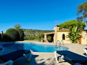een zwembad met 2 ligstoelen naast een huis bij Paliane CostaBravaSi in Calonge