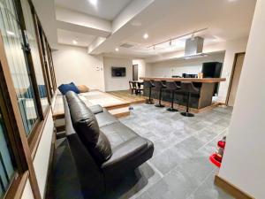 ein Wohnzimmer mit einer Ledercouch und einem Tisch in der Unterkunft Rou in Nozawa Onsen