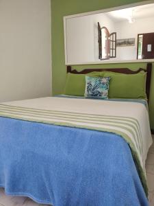 a bed with green and white sheets and a blue blanket at Espaço 579 in Miguel Pereira