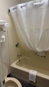 a bathroom with a toilet and a tub with a shower curtain at ArabKnightsInn in Arab
