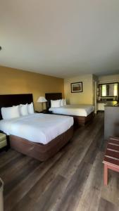 two beds in a hotel room with wooden floors at ArabKnightsInn in Arab