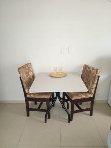 ピサーハスにあるcasaspraiagumsのテーブルと椅子2脚、白いテーブルとグラス2個