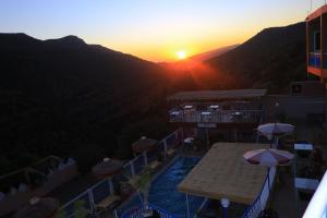 vista para um resort com piscina e pôr-do-sol em Auberge Les Montagnes du Paradis Your Hidden Retreat in Paradise Valley em Agadir