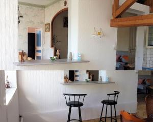 two pictures of a kitchen with two bar stools at La choletaise spacieuse et proche des axes routiers in Cholet