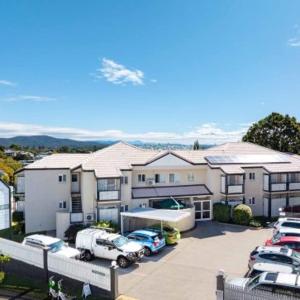 un estacionamiento con autos estacionados frente a una casa en Herston Place Motel, en Brisbane