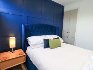een blauwe slaapkamer met een bed met een blauw hoofdeinde bij Highfield Cottage in Windermere