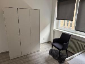 1 dormitorio con silla negra y armario en Better Homes, en Oberhausen