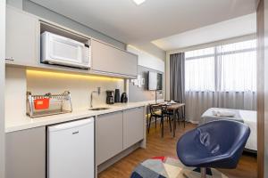 a room with a kitchen with a microwave and a table at Helbor Stay Batel in Curitiba +5 photos