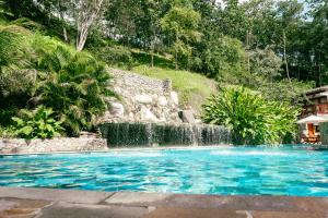 ein Swimmingpool mit Wasserfall im Garten in der Unterkunft Bio Rio Hotel in San Jerónimo