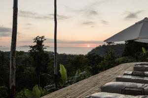 a view of the ocean from a resort with chairs and an umbrella at Mōmento Itamambuca in Ubatuba