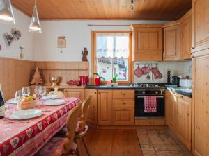 塔尔维西奥Chalet Alpino con Sauna a 4 min a piedi dalle piste da sci的厨房配有木制橱柜和一张带红色桌布的桌子。