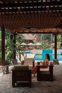 Eine Frau sitzt an einem Tisch neben einem Pool in der Unterkunft Bio Rio Hotel in San Jerónimo