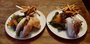 The Walkhampton Inn في Walkhampton: طبقين أبيضين عليهما شطائر وبطاطس مقلية على طاولة