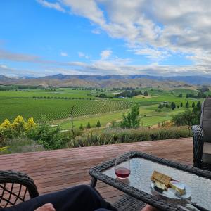 a table with a glass of wine on a wooden deck at Fairhall view 