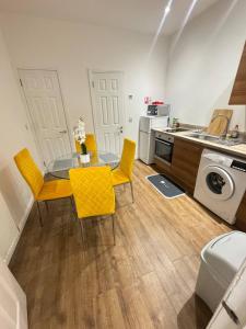 a kitchen and dining room with a table and yellow chairs at 216 High Street Abroath Apartment 1 in Arbroath +3 photos