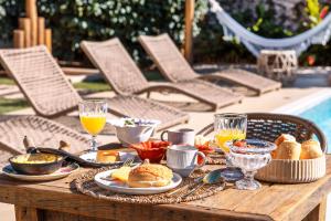 een houten tafel met ontbijtproducten en drankjes erop bij Villa Boréal Hostellerie Pousada Boutique in Águas de Lindóia +46 foto's