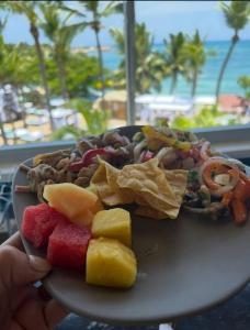 Junior Suite all inclusive luxury and tranquility by Lifestyle Resort في Maggiolo: طبق من الطعام مع الفاكهة والبطاطا المقلية والشاطئ