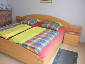 een houten bed met 2 kussens en een nachtkastje bij Hehner 2 Comfortable holiday residence in Patersberg