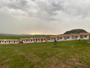 a row of houses in a field with a hill in the background at Zalu Lodge in Lusikisiki