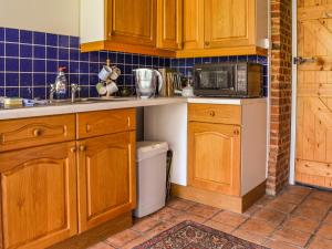 a kitchen with wooden cabinets and a microwave at Owl Barn in Sidestrand