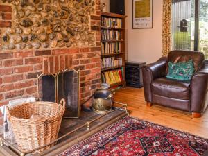 a living room with a brick fireplace and a leather chair at Owl Barn in Sidestrand