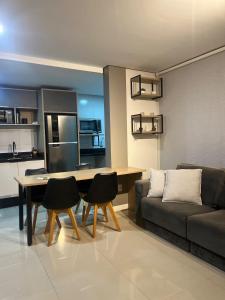 a living room with a couch and a table and chairs at Loft Completo Com Piscina, no centro in Tubarão