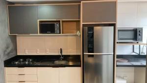 a kitchen with a stainless steel refrigerator and microwave at Loft Completo Com Piscina, no centro in Tubarão