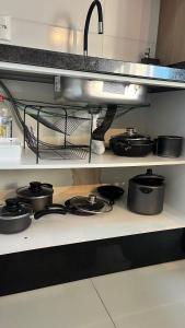 a shelf with pots and pans on a stove in a kitchen at Loft Completo Com Piscina, no centro in Tubarão +1 photo