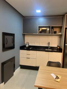 a kitchen with a table and a microwave at Loft Completo Com Piscina, no centro in Tubarão
