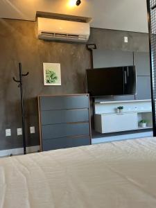 a bedroom with a bed and a tv and a cross at Loft Completo Com Piscina, no centro in Tubarão