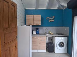 Maison cosy à Sainte-Anne - 31 m² avec terrasse في Douville: مطبخ مع ثلاجة وغسالة ملابس +5 صور