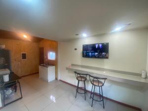 Una habitación con dos taburetes de bar y un televisor en la pared. en Departamento francisca, en Tey