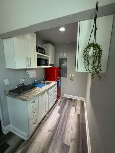 Modern Tampa studio full Kitchen & great location في تامبا: مطبخ فيه دواليب بيضاء وثلاجة حمراء +صورتان
