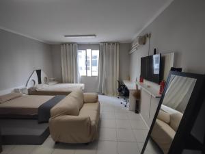 a bedroom with a couch and a bed and a tv at Apto studio 302 centro de Florianópolis in Florianópolis